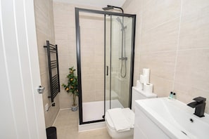 A modern bathroom with a glass-enclosed shower, a white bathtub, and a toilet. - Modern & Bright 1BED Apartment in Leeds - Sleeps 3 (Leeds)