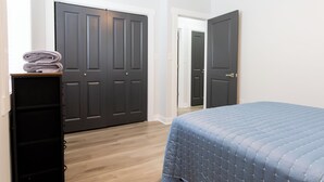 Ein Schlafzimmer mit einem Bett, einem Schminktisch und zwei geschlossenen Türen.
