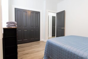 A bedroom with a bed, a dresser, and two closed doors. - Entire Home In Miller close to BP/80/94 (Gary)