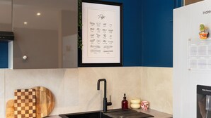 A modern kitchen with a sink, a framed pasta illustration, and a water dispenser. - Rock in share - Le Graoully (Metz)