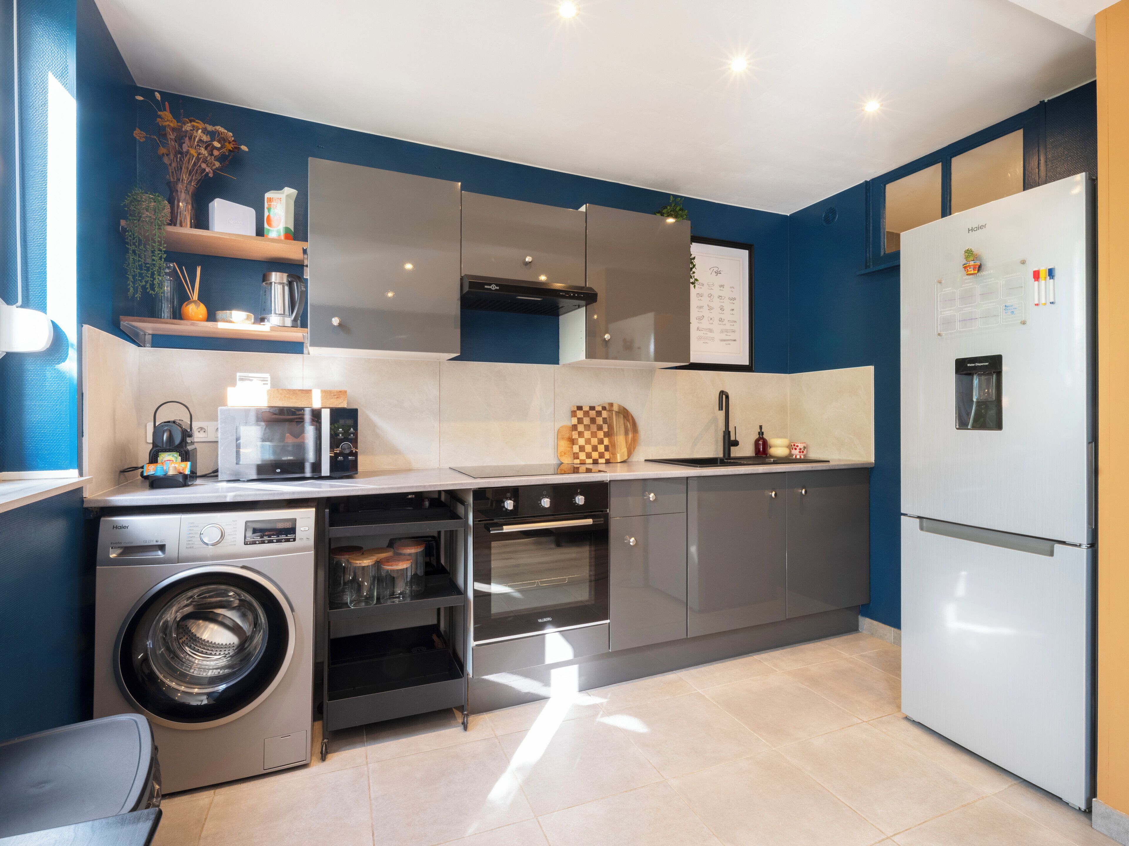 A modern kitchen with a built-in washing machine, oven, and a refrigerator.