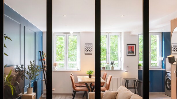 A modern kitchen with a dining area, large windows, and a view of greenery outside. - Rock in share - Le Graoully (Metz)