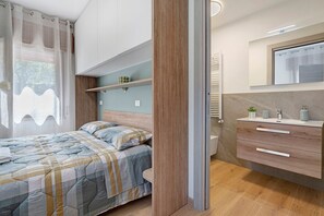 A modern bedroom with a bed, bedside table, and a built-in wardrobe.