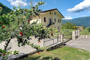 A two-story building with a balcony, a stone wall, and a metal gate.