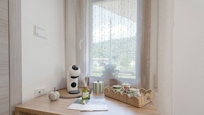 Ein Zimmer mit einem Holztisch, einem Fenster mit Blick auf Grünflächen, einer weißen Wand und einer Steckdose.