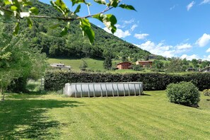 A grassy area with a large cylindrical structure, a hedge, and a building in the background. - Dolomites Room with Mountain View, Wi-Fi and Air Conditioning (Alano di Piave)
