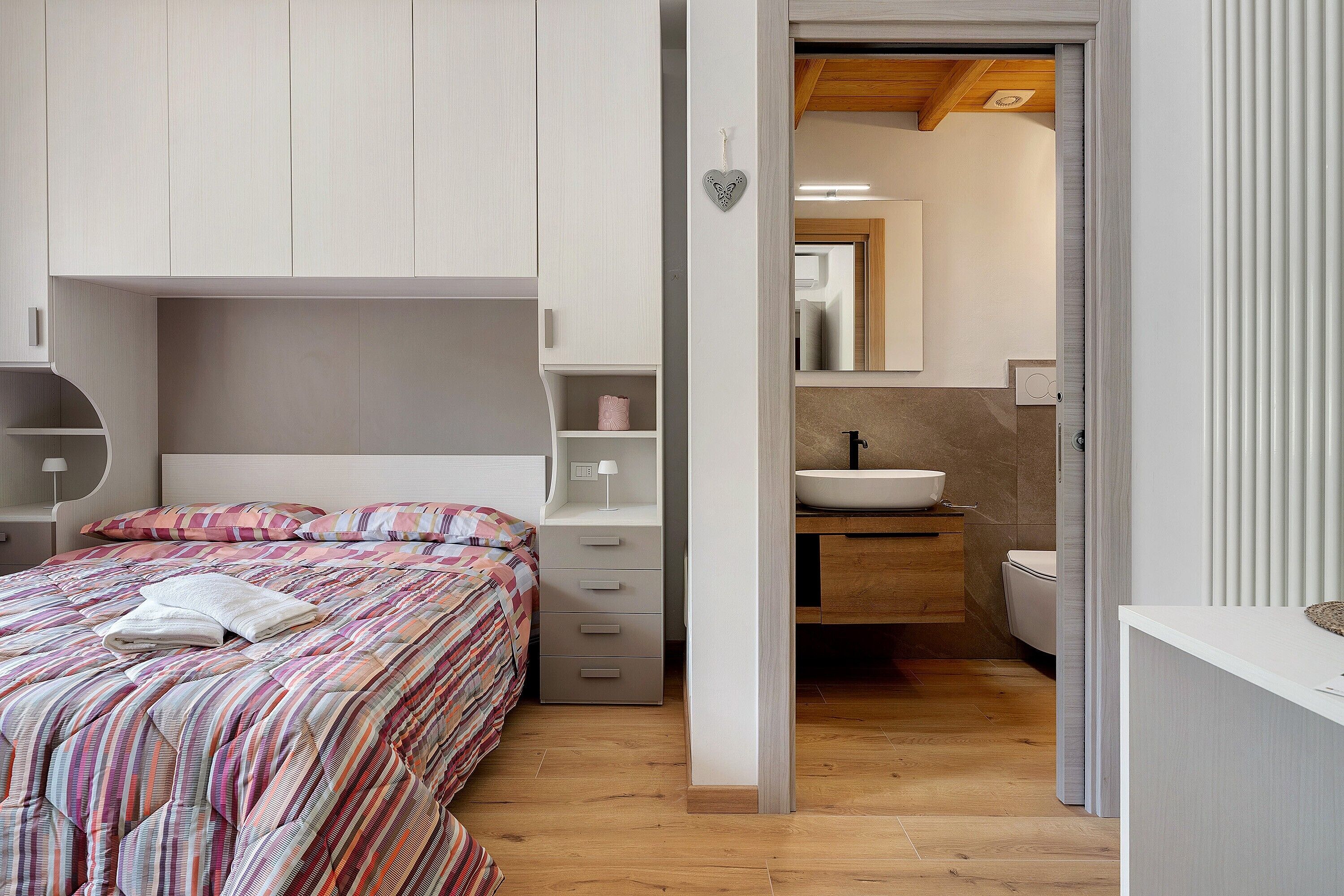 Un dormitorio con cama, mesita de noche y armario.