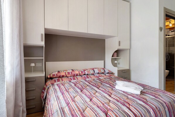 A bedroom with a bed, a wardrobe, and a bathroom visible through an open door.