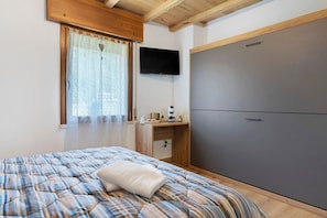 Une chambre à coucher comprenant un lit, un bureau, une télévision et une armoire.