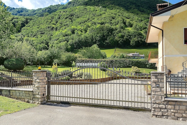 Une propriétéClose, entourée d’un mur de pierre et dotée d’un portail en métal, offrant une vue sur une colline verdoyante.