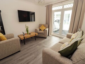 A modern living room with a sofa, a coffee table, and a TV mounted on the wall. - William's Place (Barry)