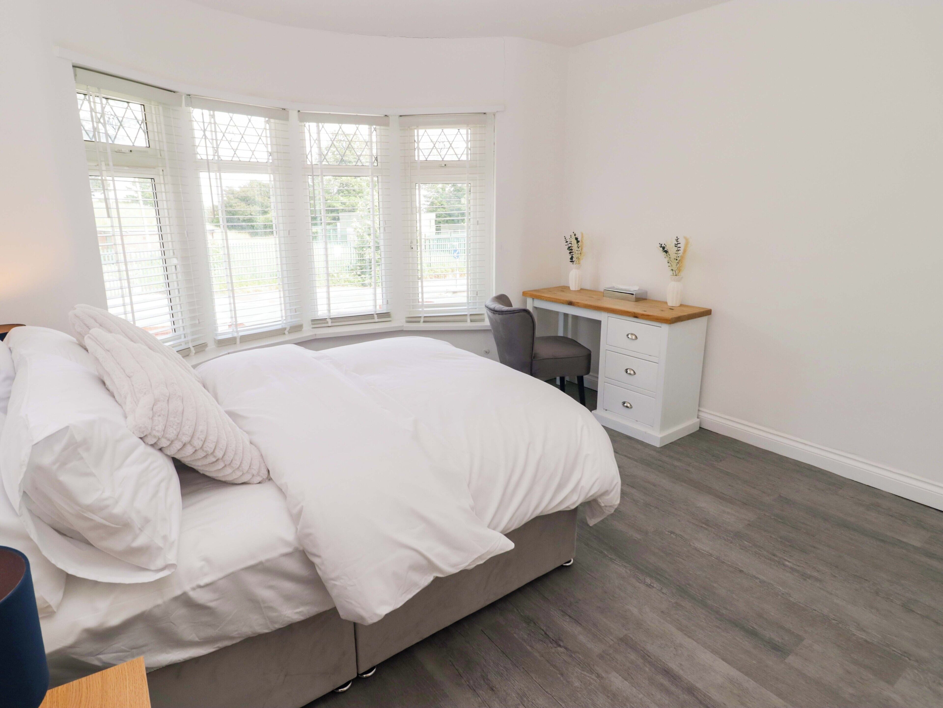 Un dormitorio con cama, escritorio y silla.