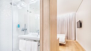 A modern bathroom with a glass shower enclosure, a white sink, and a wooden floor. - Moov Hotel Matosinhos Sul (Matosinhos)