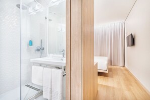 A modern bathroom with a glass shower enclosure, a white sink, and a wooden floor. - Moov Hotel Matosinhos Sul (Matosinhos, Portugal)