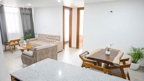 Ein modernes Wohnzimmer mit einer Couch, einem Couchtisch und einem Esstisch mit Stühlen.