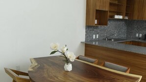 Eine moderne Küche mit einer zentralen Kochinsel, Holzschränken und einem Essbereich mit rundem Tisch und Stühlen.