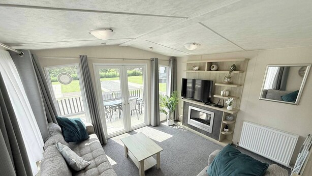 A living room with a sofa, TV, fireplace, and a view to the outside. - Golden Palm The Retreat 38, Sleeps 6 Pet Friendly (Skegness)