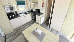 A compact kitchen with a microwave, stove, sink, and cabinets. - Golden Palm The Retreat 38, Sleeps 6 Pet Friendly (Skegness)