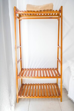 Ein Holzregal mit einer oberen Ablage und zwei unteren Ablagen vor einer weißen Wand.