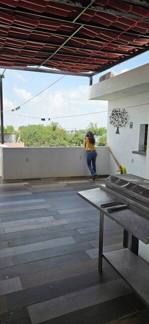 A covered outdoor area with a metal table, a wall with a tree decoration, and a person walking. - Hotel Punto Oriente: 2 Beds, A/C, and Free Parking (Tonalá)