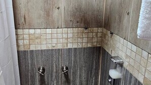 Eine Dusche mit Handbrause, ein Glas Wasser und eine Seifenspender.