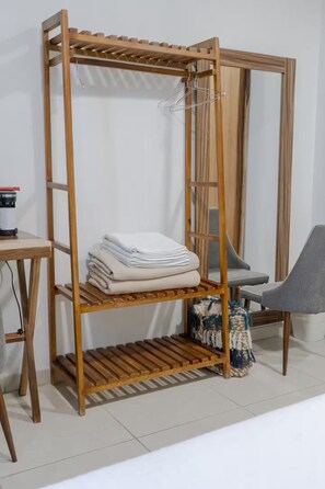Ein Regal aus Holz mit gefalteten Handtüchern, einem Stuhl und einem kleinen Tisch.