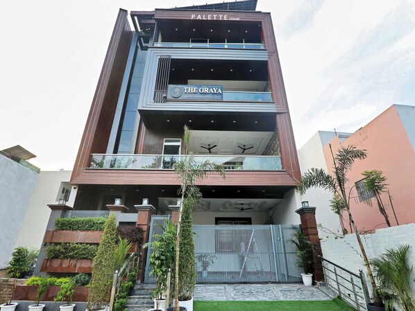 A multi-story building with balconies, a sign for 'The Oraya,' and a gated entrance. - Palette The Oraya Greens (Lucknow)