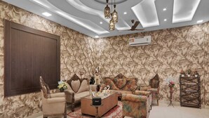 A living room with a sofa set, a coffee table, and a decorative wall. - Palette The Oraya Greens (Lucknow)