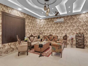 A living room with a sofa set, a coffee table, and a decorative wall. - Palette The Oraya Greens (Lucknow)