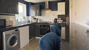 Een moderne keuken met een ingebouwde wasmachine, donkere kastjes en een marmeren aanrecht.