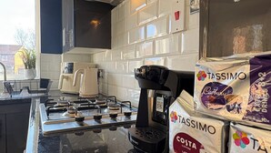 Een keuken met een zwart aanrecht, een Bosch koffiezetapparaat en Tassimo koffiecups.