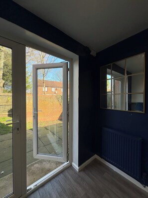 A room with a sliding glass door leading to a patio, a dark blue wall, and a radiator.