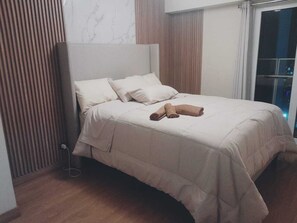 A neatly made bed with a headboard, a bedside table, and a window with curtains. - peru in hosting (Cusco)
