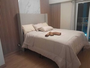 A neatly made bed with a headboard, a wooden floor, and a window with a view. - peru in hosting (Cusco)