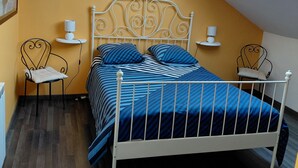 A bedroom with a sloped ceiling, a bed with a white metal frame, two bedside tables with lamps, and a skylight. - Vacation rental near the salt marshes (Batz-sur-Mer)