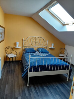 A bedroom with a sloped ceiling, a bed with a white metal frame, two bedside tables with lamps, and a skylight. - Vacation rental near the salt marshes (Batz-sur-Mer)