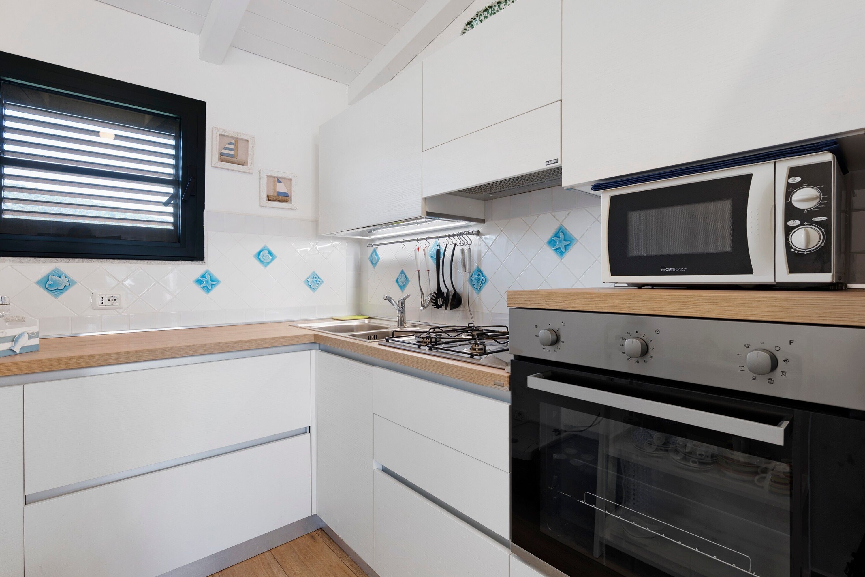 Una cucina moderna con mobili bianchi, un fornello a gas, un forno e un microonde.