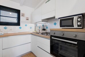 Une cuisine moderne avec des meubles blancs, une cuisinière à gaz, un four et un four à micro-ondes.