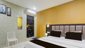 A hotel room with a bed, a chair, a wall-mounted air conditioner, and a door with a decorative glass panel. - Classic Medical College Basaratpur (Gorakhpur)