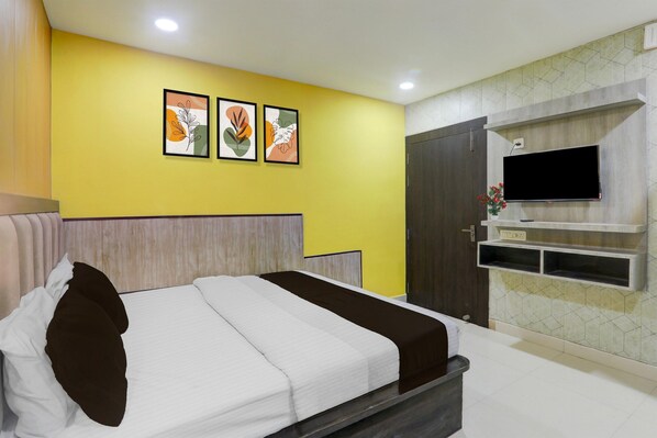 A hotel room with a bed, a TV, and artwork on the wall.