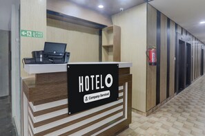 Ein Hotelrezeptionstresen mit einem Schild, das die betriebliche Betreuung anzeigt, einem Brandschutztürschild und einem an der Wand befestigten Feuerlöscher.