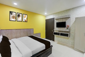 A bedroom with a bed, a TV mounted on the wall, and a wardrobe.