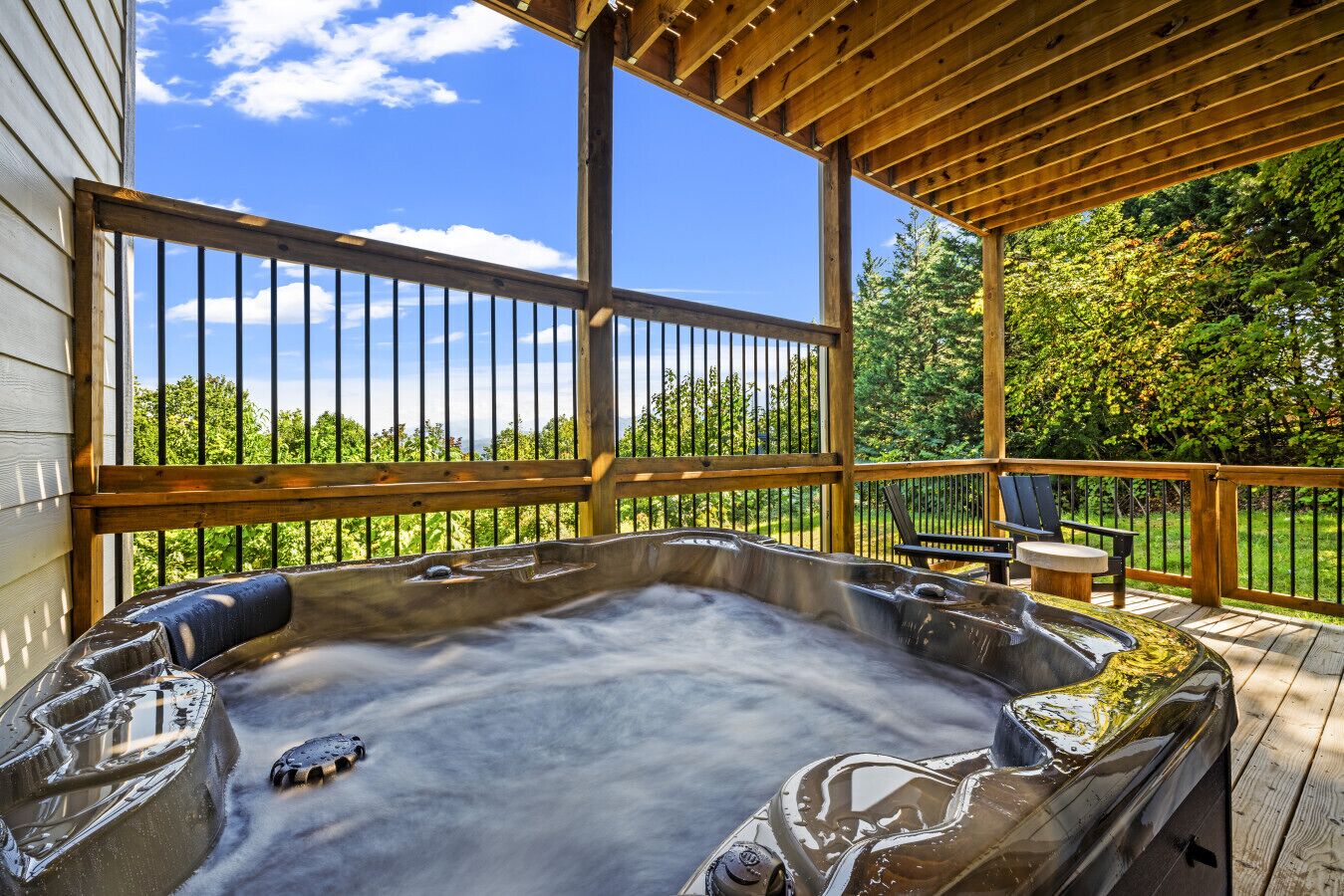 Un bain à remous sur une terrasse en bois, avec vue sur les arbres et un ciel dégagé.
