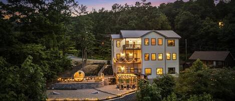 A multi-story hotel with a balcony and outdoor seating area, surrounded by trees.