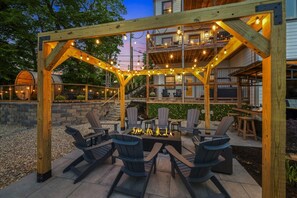An outdoor seating area with Adirondack chairs, a fire pit, and string lights. - New! Views, Sauna Spa Hottub Cantina, Dogs (Gatlinburg)