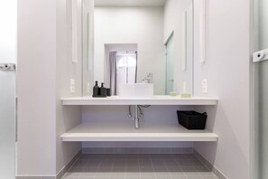 Ein modernes Badezimmer mit einem weißen Waschbecken, Spiegel und grauen Fliesenboden.