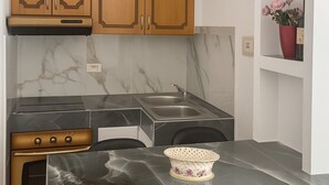 Une cuisine moderne avec des meubles en bois, un pare-feu en marbre, un évier en acier inoxydable et une table à manger avec des chaises.