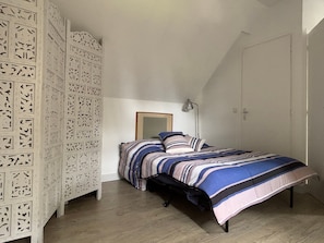 A bedroom with a bed, a nightstand, a lamp, and a wardrobe with patterned doors.