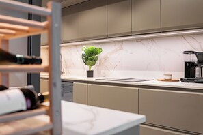 Eine moderne Küche mit Marmorarbeitsplatten, einer Kaffeemaschine und einem Topfpflanzen.