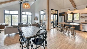 A spacious kitchen with a wooden island, bar stools, and a large window.
